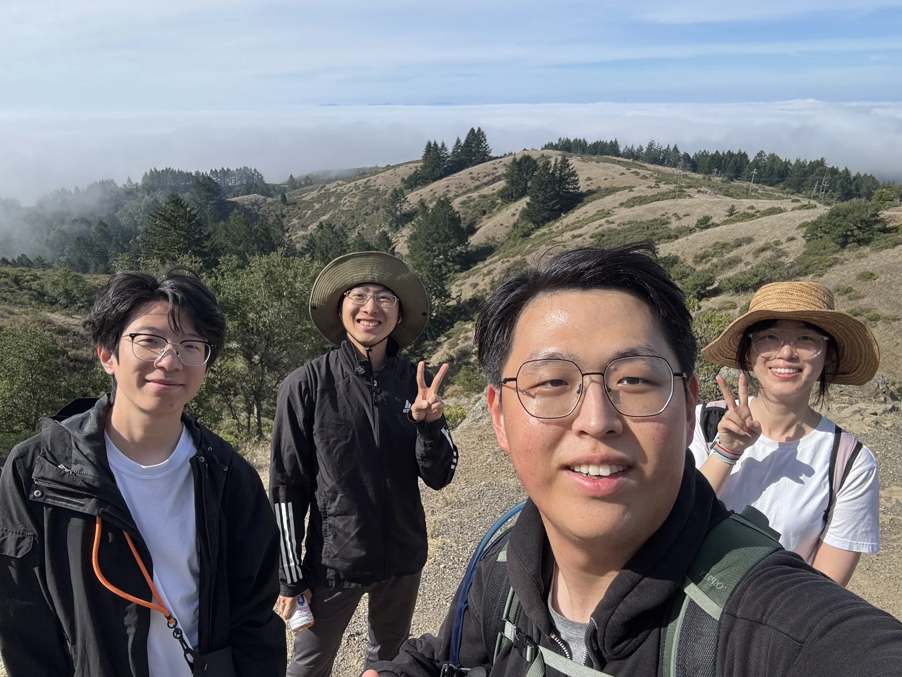 Hejia and three friends smiling on a grassy ridge
